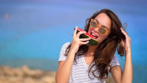 Mujer sonriente comiendo sandía en la playa en cámara lenta. Emoción femenina — Vídeos de Stock