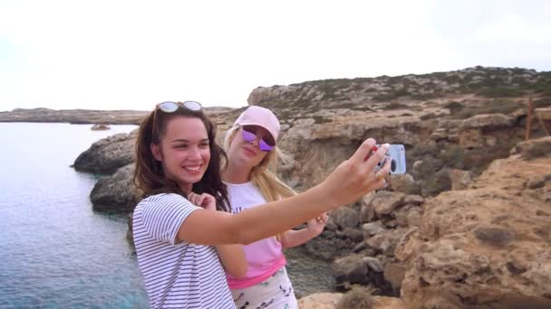 Pretty girls make selfie photo on sea in slow motion. Friends take self portrait — Stock Video
