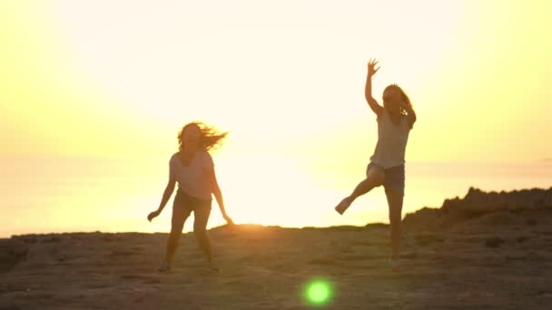 Sylwetki kobiety skoki o zachodzie słońca latem. Dwie młode dziewczyny skoki o zachodzie słońca — Wideo stockowe
