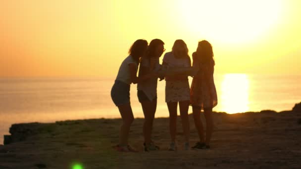 Quattro turisti con mappa al tramonto sulla spiaggia. Donna estate parlando sul tramonto del mare — Video Stock