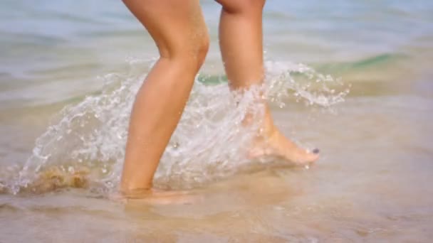 Patas femeninas en olas marinas. Las piernas de niña disfrutan de salpicaduras de agua de verano. Vacaciones de verano — Vídeo de stock