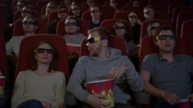 3D film izlerken ve patlamış mısır yemek sinemada oturan genç insanlar