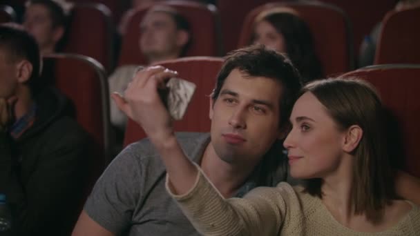 Un beso selfie en el cine. Pareja feliz haciendo selfie en el cine — Vídeo de stock