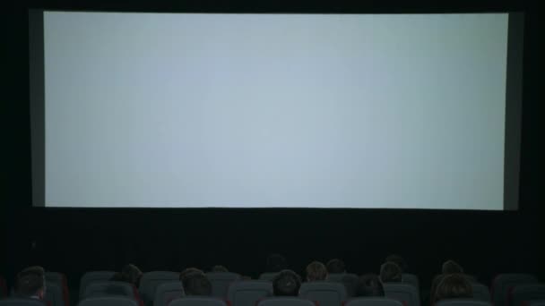 Large white screen in cinema. Beginning film in cinema. Cinema screen people — Stock Video