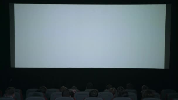 Zuschauer applaudieren in Erwartung der Filmvorführung vor weißer Leinwand — Stockvideo