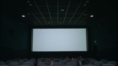 Beyaz ekran önünde oturan seyirci. Sinemada alkışlamak insanlar