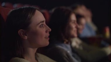Gülümseyen kız tiyatro performans izliyor ve gülüyor. Seyirci iyi eğlenceler. Sinema insanlar komedi film izlerken. Ağır çekimde sinemada komik film izlerken kadın yüz yakın çekim