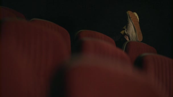 Man sleeping in empty cinema hall. Sleeping man feet on cinema chair — Stock Video