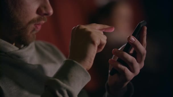 Przy użyciu telefonu komórkowego w kinie męskie dłonie. Ręce człowieka przewijanie telefon w teatrze — Wideo stockowe