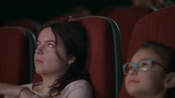 Adolescente assistindo filme no cinema com irmã mais nova — Vídeo de Stock