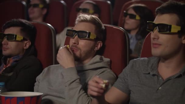 Amigos comiendo palomitas en el cine. La gente viendo películas en gafas 3d — Vídeo de stock