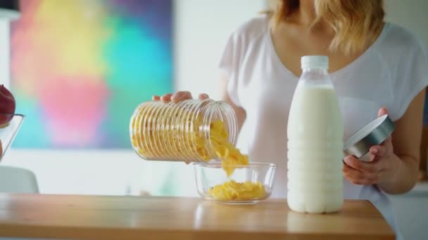 Vrouw handen voorbereiden ontbijtgranen met melk op keukentafel — Stockvideo