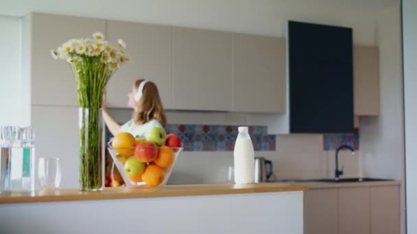 Mujer feliz escuchando música con smartphone en la cocina. Chica feliz — Vídeo de stock