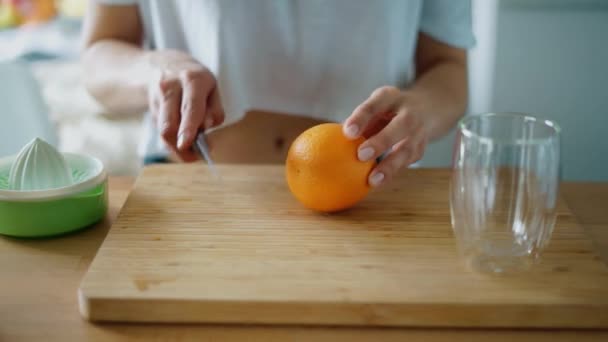 Narancs gyümölcsöt szeletelek a friss gyümölcslé préseléséhez. Női kezek közelsége — Stock videók