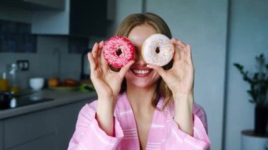 Gülümseyen kız sırlı donuts gözleriyle kapsayan. Güzel kadın eğleniyor
