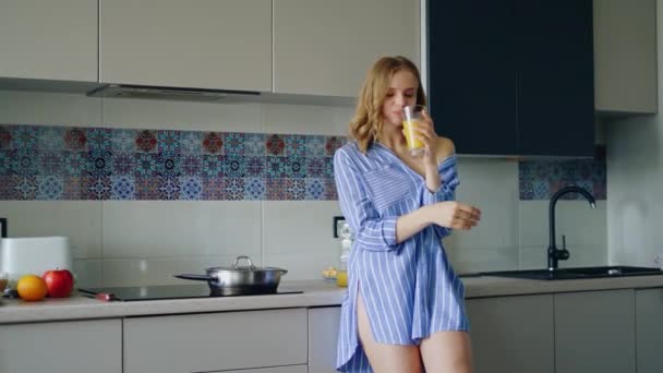 Sexy Mädchen in Nachthemd trinkt Orangensaft aus Glas. Mädchen genießen Saft — Stockvideo