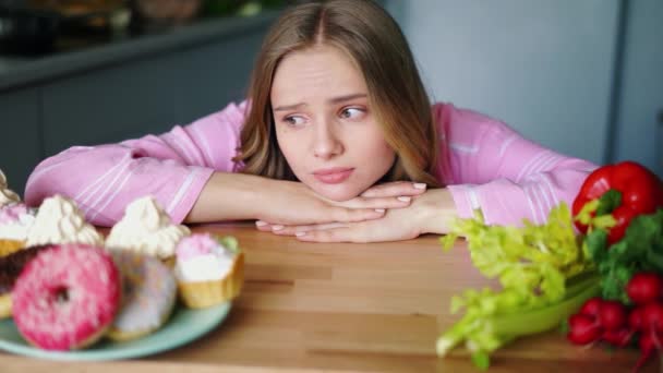 Triest jonge vrouw op zoek op gezonde en ongewenste voedsel afwisselend — Stockvideo