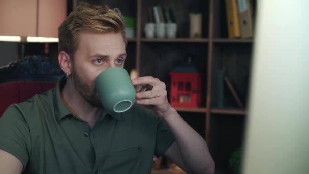 Diseñador creativo bebiendo té en la oficina de inicio. Hombre mirando en la pantalla del ordenador — Vídeo de stock