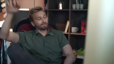 Yakışıklı adam bilgisayardan geri yaslanmış. Kırık sandalyeden düşen çalışan