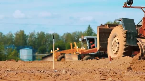 Мотогрейдер выравнивает землю на строительной площадке. Грязная тяжелая техника — стоковое видео