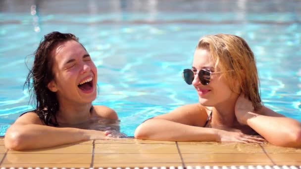Две девушки смеются в бассейне. Красивые девушки проводят время в отпуске — стоковое видео