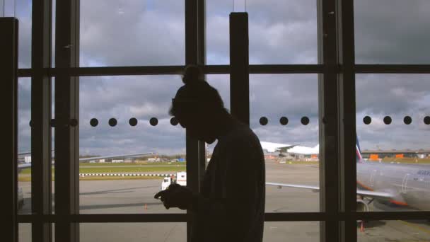 Silueta de hombre cerca de la ventana del aeropuerto. Hombre en la ventana del aeropuerto — Vídeo de stock