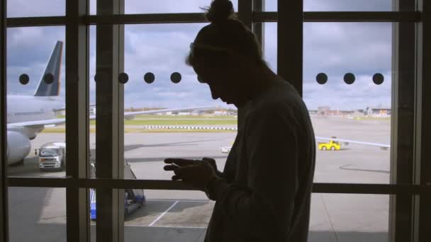 Человек, использующий мобильный смартфон в аэропорту ждет самолет — стоковое видео