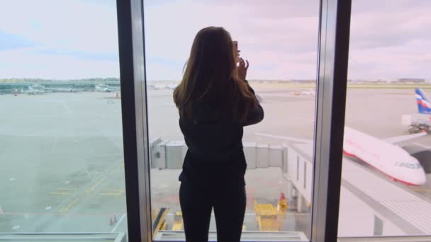 Młoda dziewczyna Dokonywanie wideo smartfonem lądowania samolotów na lotnisku — Wideo stockowe