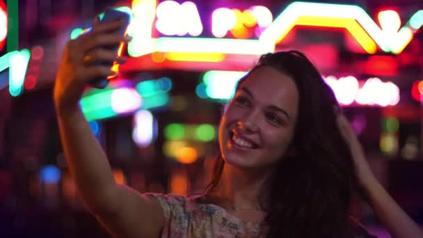 Kvinnlig turist tar natt selfie. Vacker flicka att göra selfie i staden ljus — Stockvideo