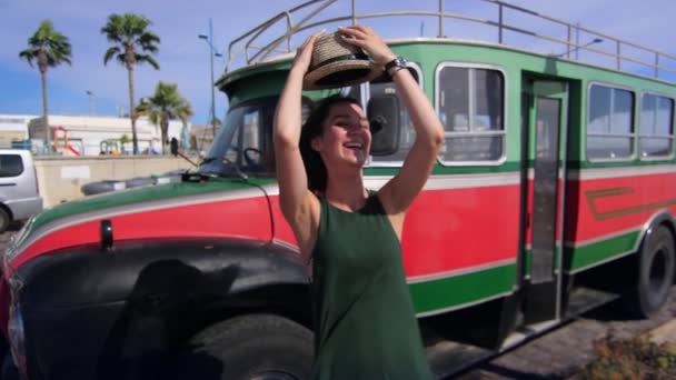 Radosna dziewczyna w kapeluszu pozowanie aparatu na tło vintage autobus. Hipster stylu życia — Wideo stockowe