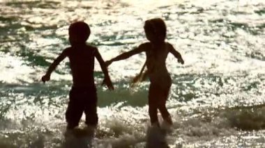 Çocuklar gün batımı dalgalar iyi eğlenceler. Mutlu tatil. Çocuklar suyun keyfini çıkarın.