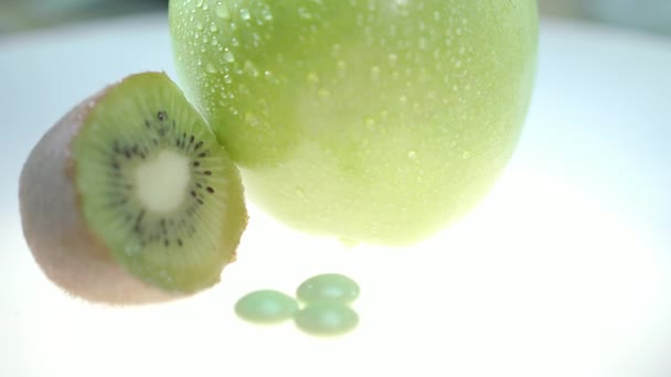 Grüne Kiwi Und Apfelfrüchte Mit Vitamintablette Auf Weißem Hintergrund Vitaminpillen — Stockvideo