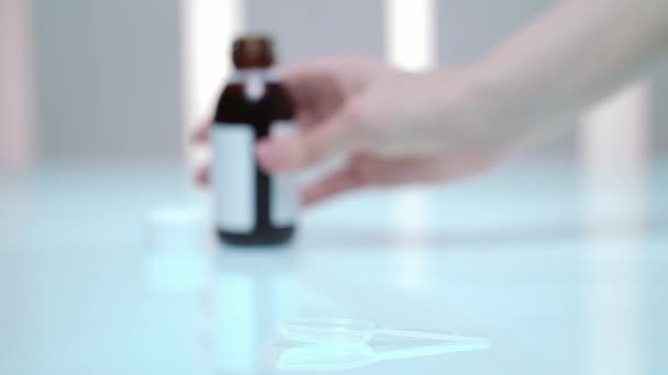 Main de femme versant du sirop de médecine. Posologie du médicament liquide. Traitement de la grippe 