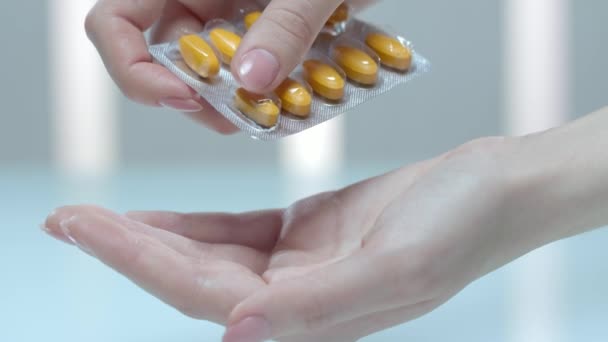 女性の手は、ブリスターの錠剤からビタミン錠剤を取る。ビタミンの錠剤薬 — ストック動画