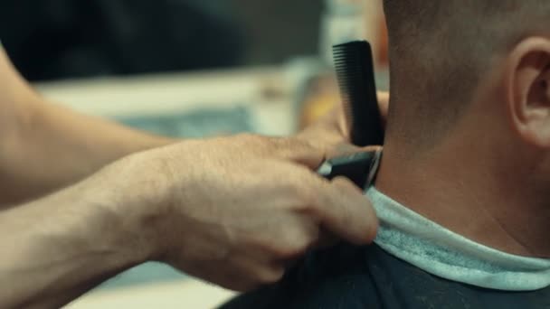 Парикмахер стрижет волосы клиента-мужчины. Закройте руки парикмахеру делая стрижку — стоковое видео