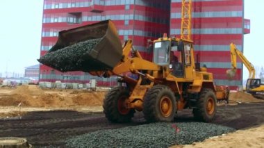 İnşaatta çalışan Yükleyici-Tekerlekli yükleyici. Ekskavatör ezilmiş taş kaldırır