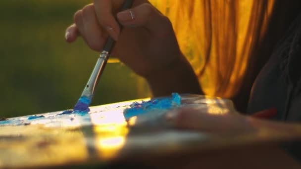 Vrouw kunstenaar schilderen bij zonsondergang buitenshuis. Close-up van vrouw handen verf mengen — Stockvideo