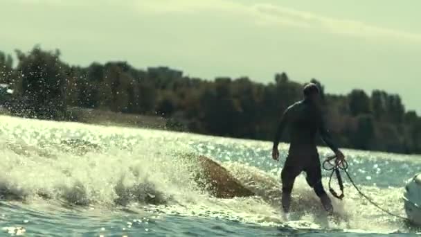 Активный спортсмен вейкбординг на волнах на реке и бросание веревки — стоковое видео