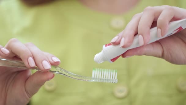 Закройте женские руки, сжимая зубную пасту на зубной щетке. Концепция гигиены полости рта — стоковое видео