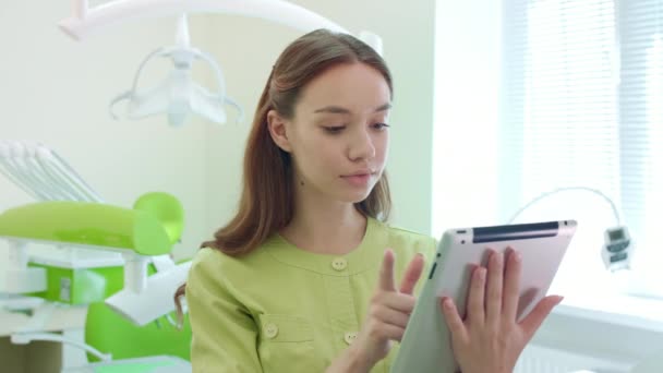 Estudiante de medicina trabajando en la tableta PC en el consultorio dental. Mujer doctora usando tableta — Vídeos de Stock