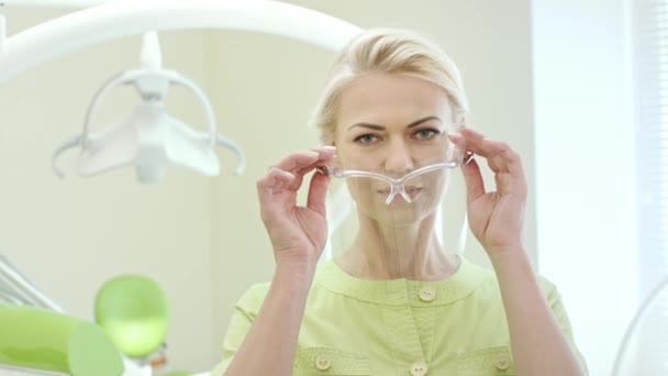 Kvinnliga tandläkare klä upp skyddsglasögon. Kvinna läkare förbereda för arbete — Stockvideo