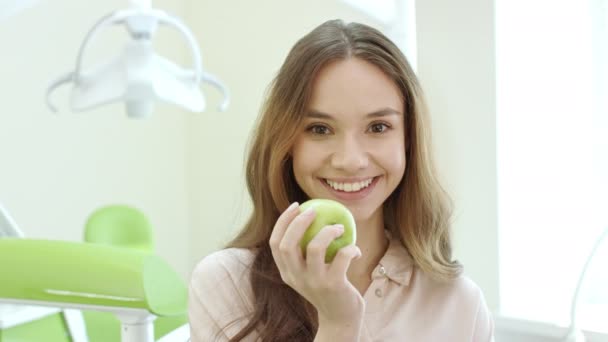 Mujer feliz comiendo manzana en la clínica dental. Paciente sonriente en el consultorio del dentista — Vídeos de Stock