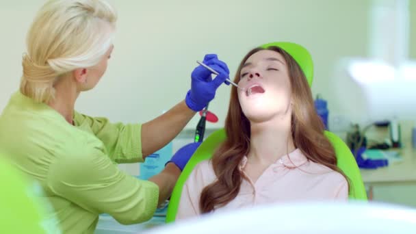 Estomatólogo usando luz de curado dental para cavidad oral. Dentista y paciente — Vídeos de Stock