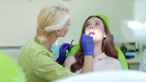 Регулярний огляд зубів у стоматологічному кабінеті. Щаслива жінка на стоматологічному стільці — стокове відео