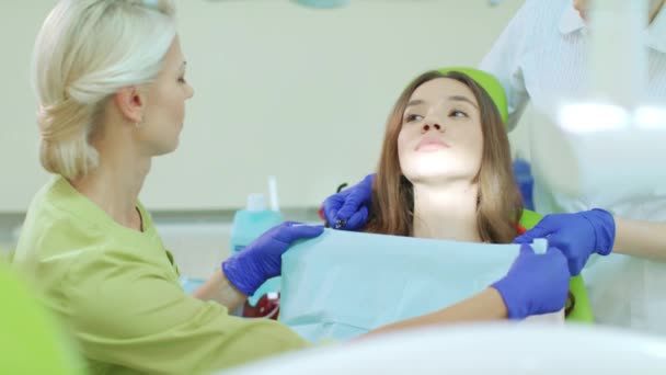 Dentista con asistente preparándose para el tratamiento dental. Paciente en silla de dentista — Vídeos de Stock