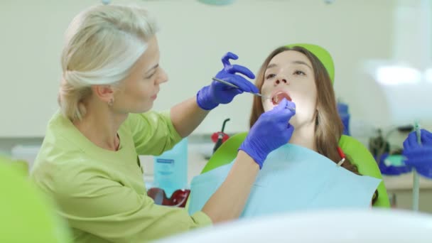 Dentista examinando los dientes del paciente con herramientas dentales. Médico y paciente — Vídeos de Stock