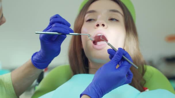 Dentista feminina examinando os dentes do paciente com ferramentas dentárias. Tratamento médico — Vídeo de Stock