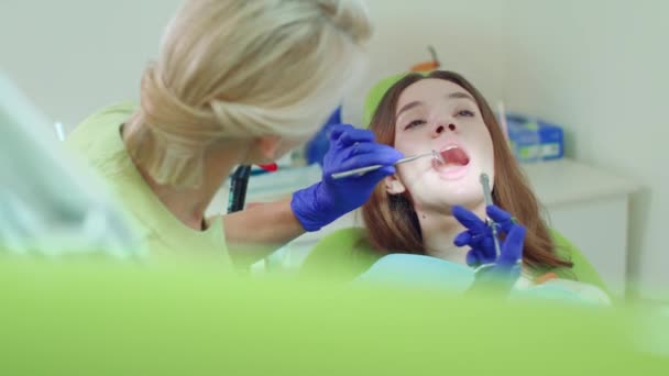 Дантист, делающий анестезию молодой женщине. Женщина-дантист с зеркалом во рту — стоковое видео