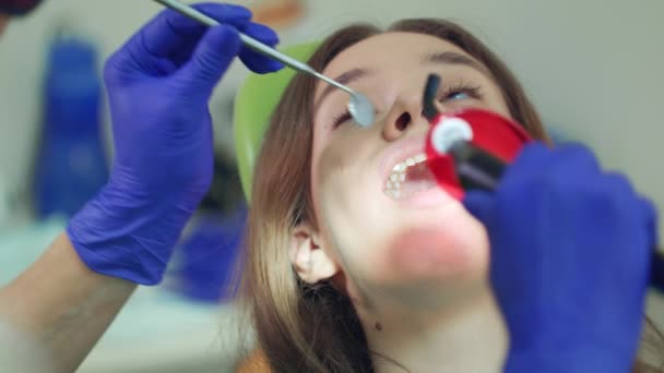 Paciente mulher em procedimento dentário. Trabalho de dentista com lâmpada de polimerização dentária — Vídeo de Stock