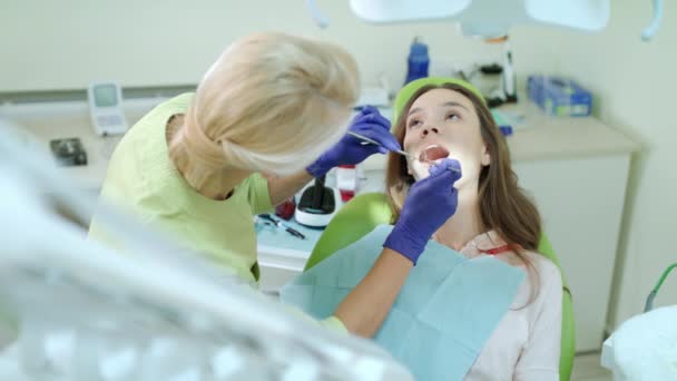 Higienista dentário examinando os dentes do paciente com espelho bucal e sonda dentária — Vídeo de Stock